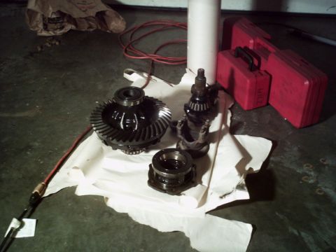 1986 Ford Bronco - Several automotive differential components are laid out on a white sheet, with toolboxes and a cord nearby.