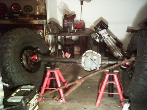 1986 Ford Bronco - A Dana 60 axle assembly is shown on jack stands, with large tires visible.