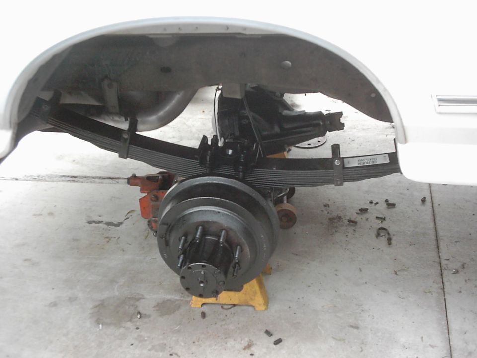 Rear axle assembly with leaf springs and brake drum, supported by jack stands