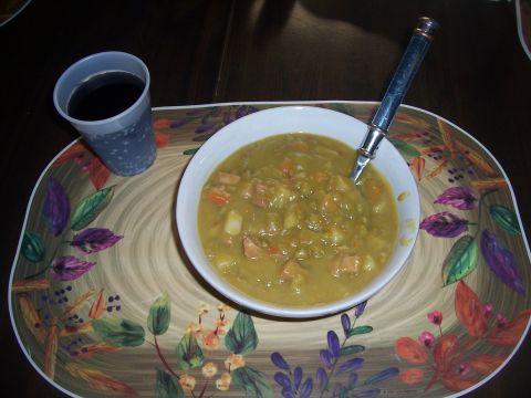 1995 Ford Bronco - A close-up view of a bowl of split pea soup with ham, accompanied by a cup of dark liquid on a placemat.