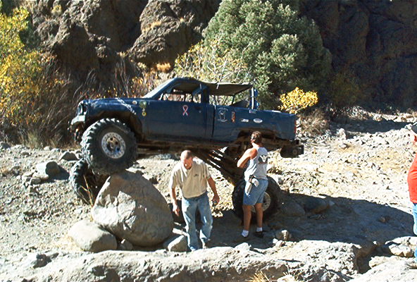 Dark blue off-road vehicle with large tires navigating rocky terrain