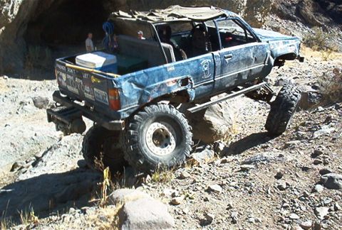 1986 Ford Bronco - Heavily modified pickup truck navigating a rocky, off-road trail.