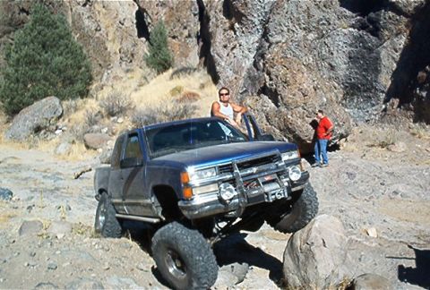 1986 Ford Bronco - This blue pickup truck, likely a 1995 model, navigates rocky terrain with a winch mounted on the front bumper.