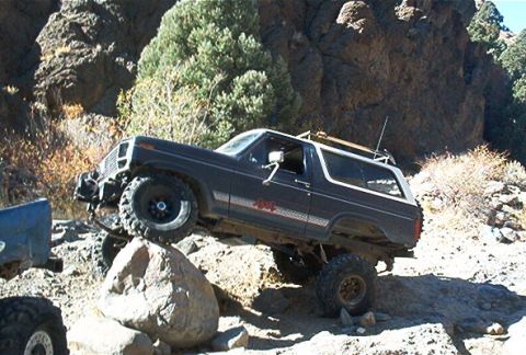 1986 Ford Bronco - This Ford Bronco is navigating a rocky off-road trail with its tires on large boulders.