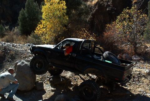 1986 Ford Bronco - A modified pickup truck navigates a rocky obstacle course on an off-road trail.