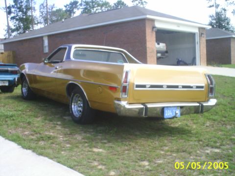 1973 Ford Ranchero - Rear view of a gold 1973 Ford Ranchero pickup truck parked on grass near a brick house.