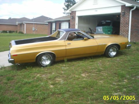 1973 Ford Ranchero - A gold 1973 Ford Ranchero is parked on a grassy lawn in front of a suburban house and garage.