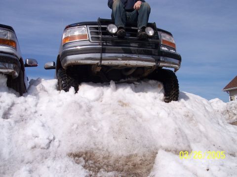 1995 Ford Bronco - A person sits on the hood of a Ford Bronco parked on a snowdrift, with another vehicle visible to the left.