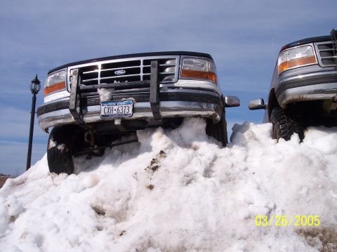 1995 Ford Bronco - Two Ford trucks are partially buried in snow, with the front of one vehicle prominently displayed.