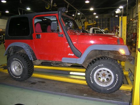 2001 Jeep Wrangler - This red Jeep TJ is on a lift in a garage, equipped with a snorkel and off-road tires.