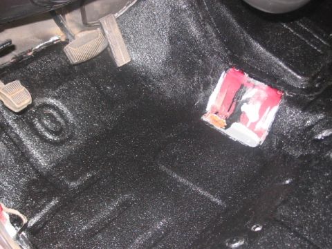 1991 Ford Bronco - The floor of a vehicle has been coated with a textured black material, with pedals visible.