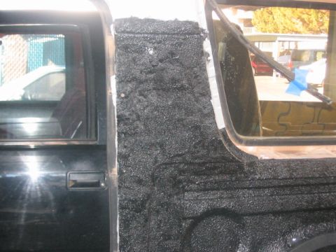 1991 Ford Bronco - Close-up of a vehicle's interior showing a black door and a rough textured panel near the window.