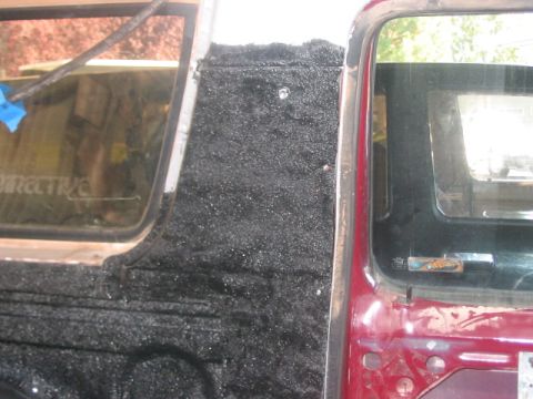 1991 Ford Bronco - Close-up view of the interior door panel and window frame, showing a black textured material applied.