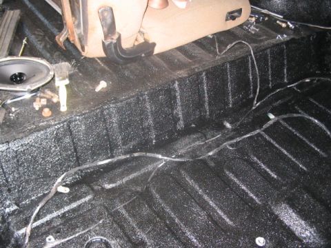 1991 Ford Bronco - Interior floor of a vehicle being worked on, showing a speaker and seat mounting hardware.