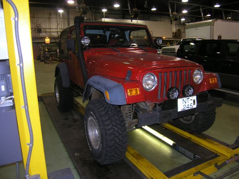 2001 Jeep Wrangler - A red Jeep Wrangler is shown on a lift in a garage, a snorkel and auxiliary lights.