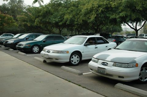 1991 Ford Taurus - A white 1991 Ford Taurus sedan is parked in a lot with other vehicles.