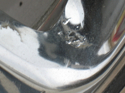 1999 Mitsubishi 3000GT - Close-up of a damaged chrome rim, showing signs of corrosion and wear.