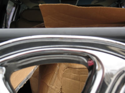1999 Mitsubishi 3000GT - Close-up of a chrome wheel, with cardboard boxes visible in the interior of the vehicle.