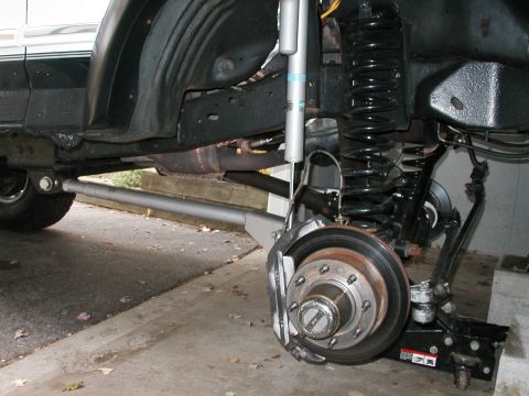 1994 Ford Bronco - The underside of a vehicle shows its suspension system, including a large coil spring and shock absorber.