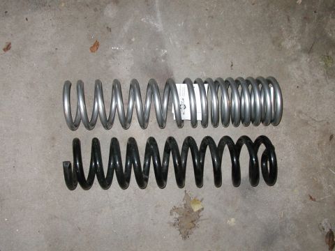 1994 Ford Bronco - Two coil springs, one silver and one black, are laid out on a concrete floor.