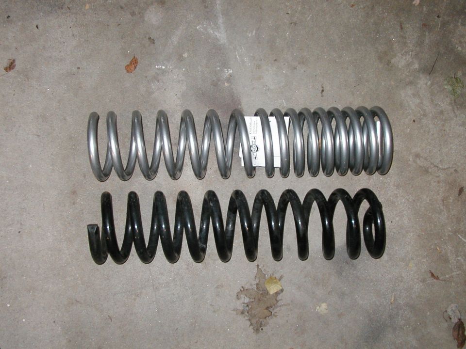 Two coil springs, one silver and one black, on a concrete surface