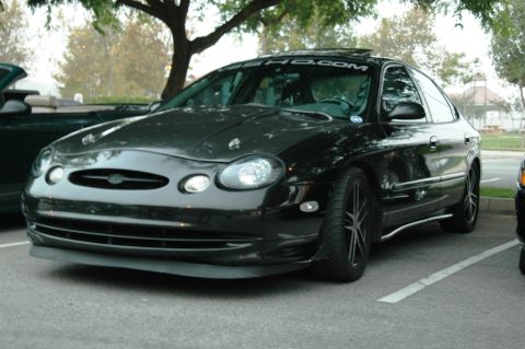 1991 Ford Taurus - This black sedan features aftermarket hood pins and a visor over the sunroof.