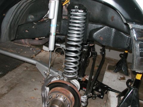 1994 Ford Bronco - Close-up of vehicle's front suspension and brake system, showing aftermarket shocks and springs.