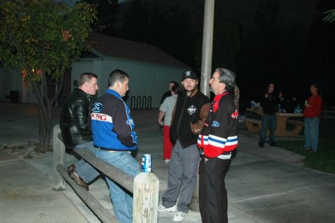 1991 Ford Taurus - Several men are gathered outdoors in the evening, some standing and some sitting on a fence.