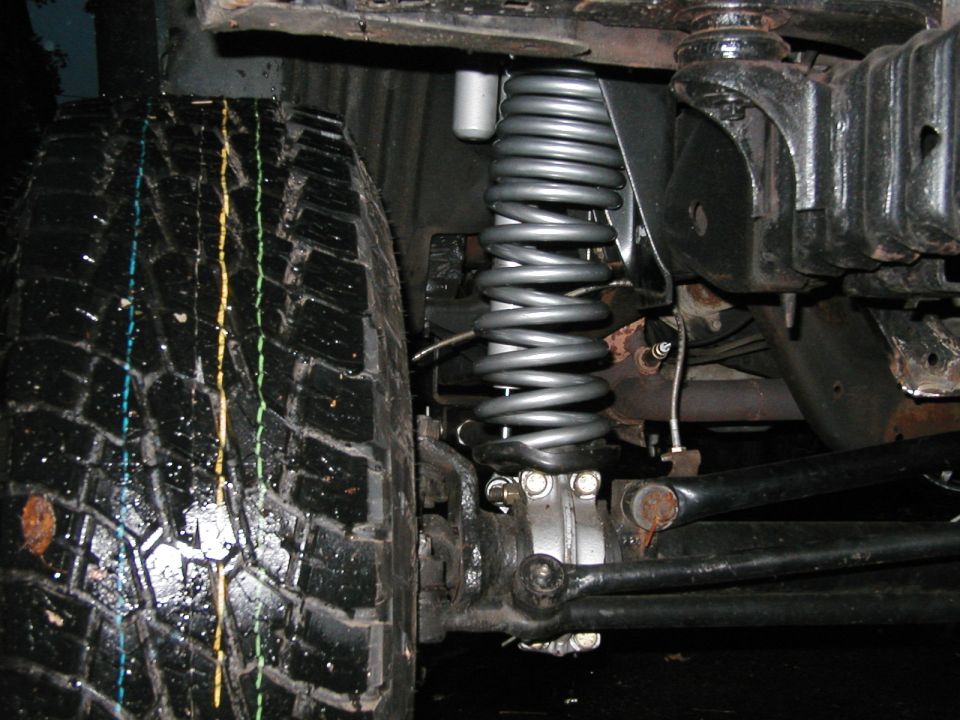 Close-up of a vehicle's front suspension coil spring and tire