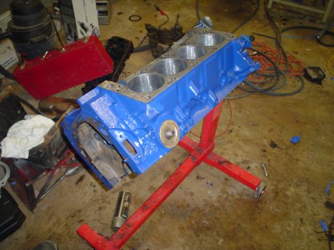 1981 Ford Bronco - A freshly painted blue engine block sits on a stand, ready for assembly in a workshop.