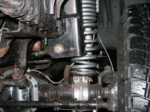 1994 Ford Bronco - Undercarriage view of a vehicle's suspension system, showing the coil spring and tire.