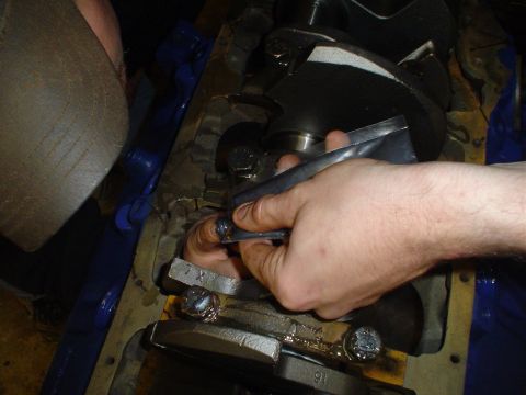 1981 Ford Bronco - Mechanic applies lubricant to a connecting rod bearing during engine assembly.