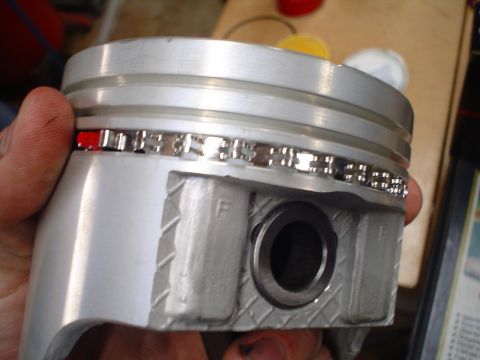 1981 Ford Bronco - A close-up view of a piston with its rings installed, showing a red-colored ring.