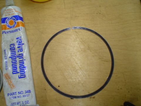 1981 Ford Bronco - A tube of valve grinding compound and a piston ring are shown on a workbench.