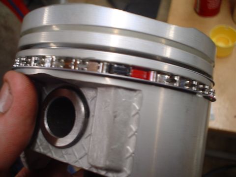 1981 Ford Bronco - A person is holding an engine piston with installed piston rings, showing detail of the ring grooves.