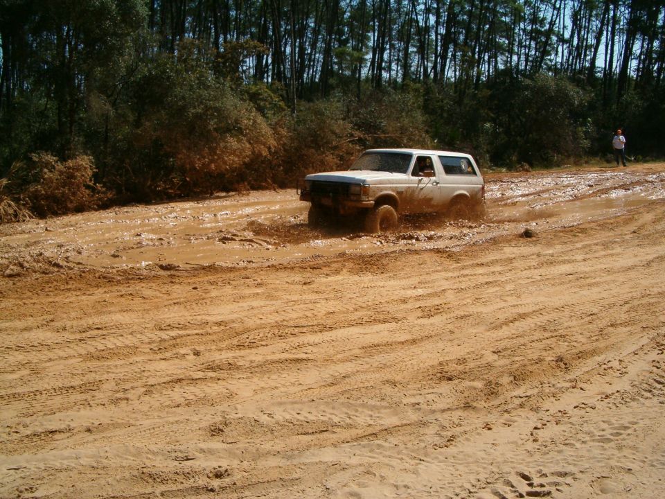 White 1991 Ford Bronco navigating a muddy track