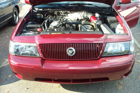 1998 Ford Crown Victoria - This red sedan's grille and headlights suggest a model year around 2003, not 1998.