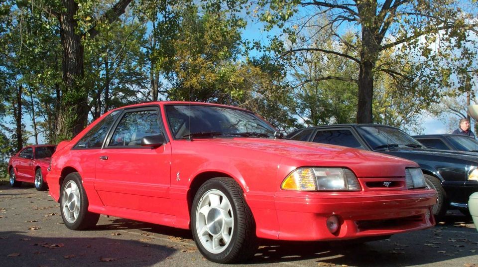 Bright red Fox-body Ford Mustang hatchback with Cobra front fascia and white wheels