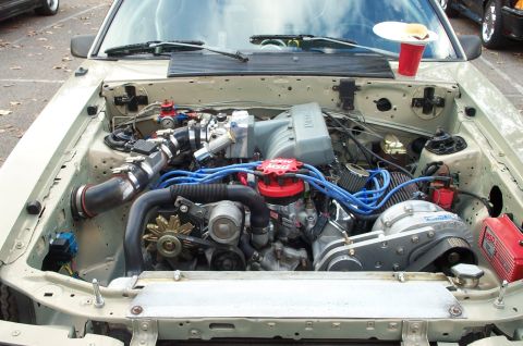 1998 Ford Crown Victoria - The engine bay of a car is shown with a prominent supercharger and custom modifications.