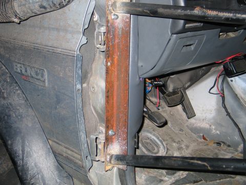 1992 Ford Bronco - Stripped driver's-side door opening of a Ford Bronco XLT with the doors removed and a bare rust-colored A-pillar showing surface corrosion,…