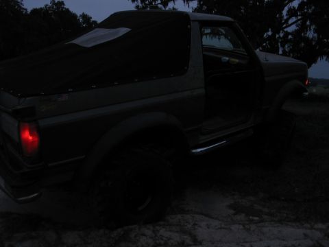 1992 Ford Bronco - A 1992 Ford Bronco is parked outdoors at dusk, its driver's door ajar and a black soft top covering the rear.