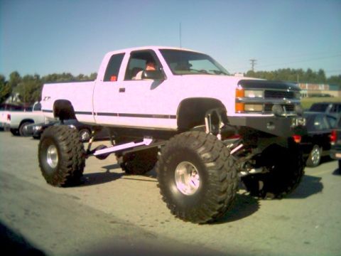 1984 Ford Bronco II - A heavily modified pickup truck with oversized tires is shown on a sunny day.