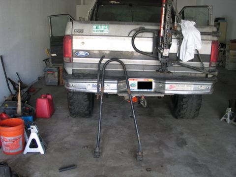 1995 Ford Bronco - A Ford F-250 truck is parked in a garage, equipped with a Hi-Lift jack and a hitch rack, suggesting preparation for an outdoor activity.
