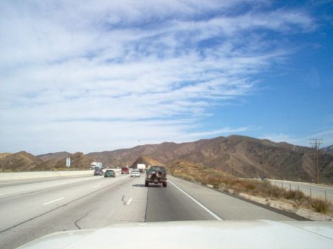 1988 Ford Bronco - Driving on a highway with mountains and other cars on a sunny day.