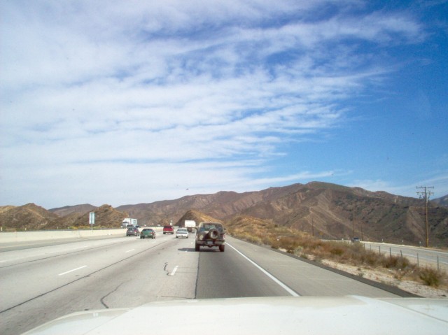 View from a car on a highway with mountains in the background and other vehicles on the road
