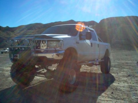 1988 Ford Bronco - White pickup truck with aftermarket modifications in a desert setting.