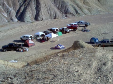 1988 Ford Bronco - A group of vehicles and camping tents are set up in a barren, mountainous desert environment.