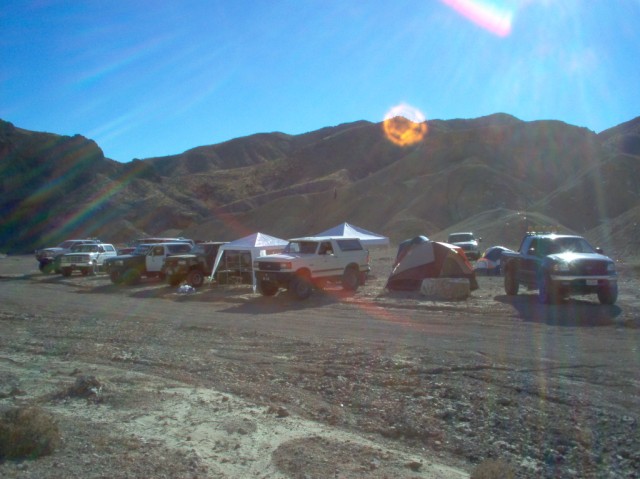 White 1987 Ford Bronco parked at a desert campsite with tents and other vehicles