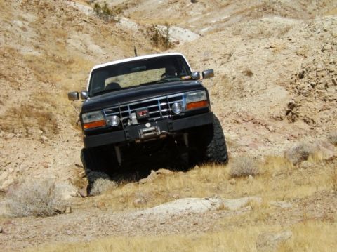 1988 Ford Bronco - Ford Bronco navigates a challenging off-road terrain with steep inclines and loose rocks.