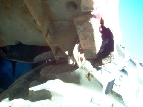 1988 Ford Bronco - Close-up view of heavily rusted vehicle frame components and a tire.